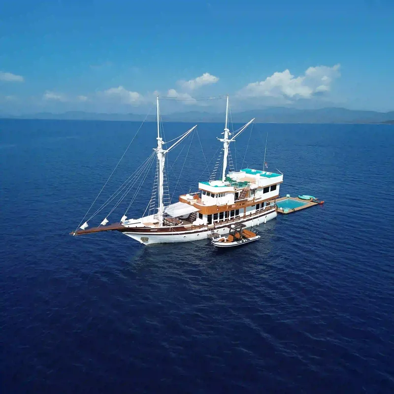 A white-hulled phinisi on deep blue water in Komodo National Park